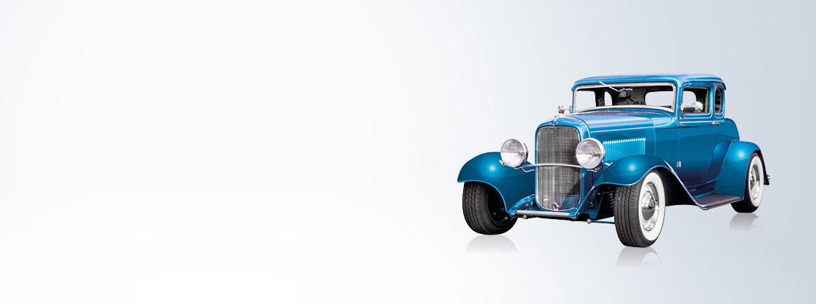 Ein blauer Hotrod-Oldtimer mit Chromdetails ist auf einem hellen Farbverlaufshintergrund nach rechts gerichtet. Das klassische Design mit großen Kotflügeln und freiliegenden Rädern spiegelt den Retro-Stil und den makellosen Zustand des Autos wider.