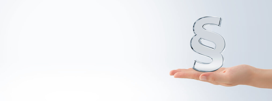 Eine Hand hält sanft ein transparentes 3D-Absatzsymbol vor einem hellgrauen Hintergrund. Das Symbol scheint knapp über der Handfläche zu schweben und suggeriert ein Gesetzeskonzept oder juristische Angelegenheiten.