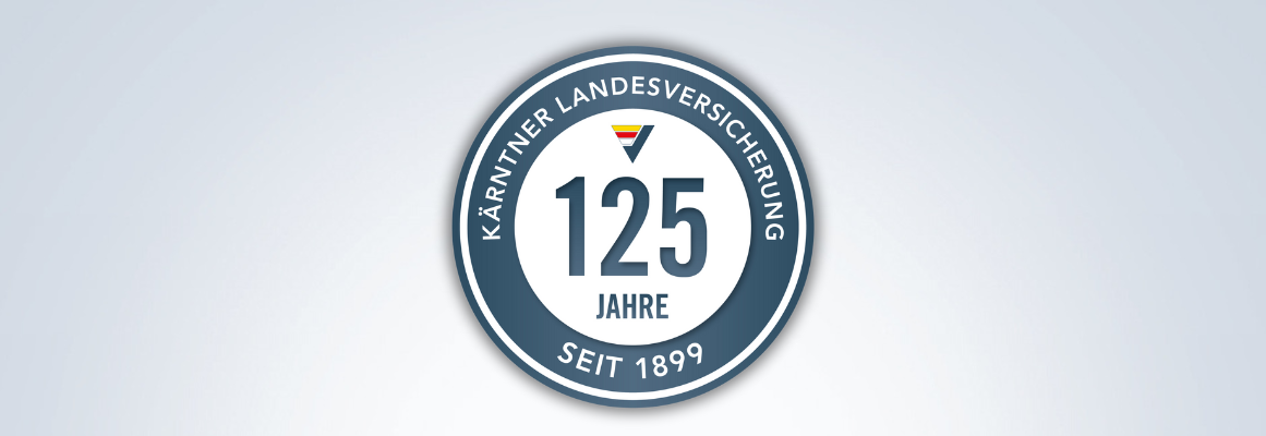 Ein kreisförmiges Emblem mit der Aufschrift „Kärntner Landesversicherung“ am äußeren Rand. In der Mitte steht „125 Jahre“, darüber eine kleine Flagge. Darunter steht „Seit 1899“. Der Hintergrund ist leicht abgestuft.